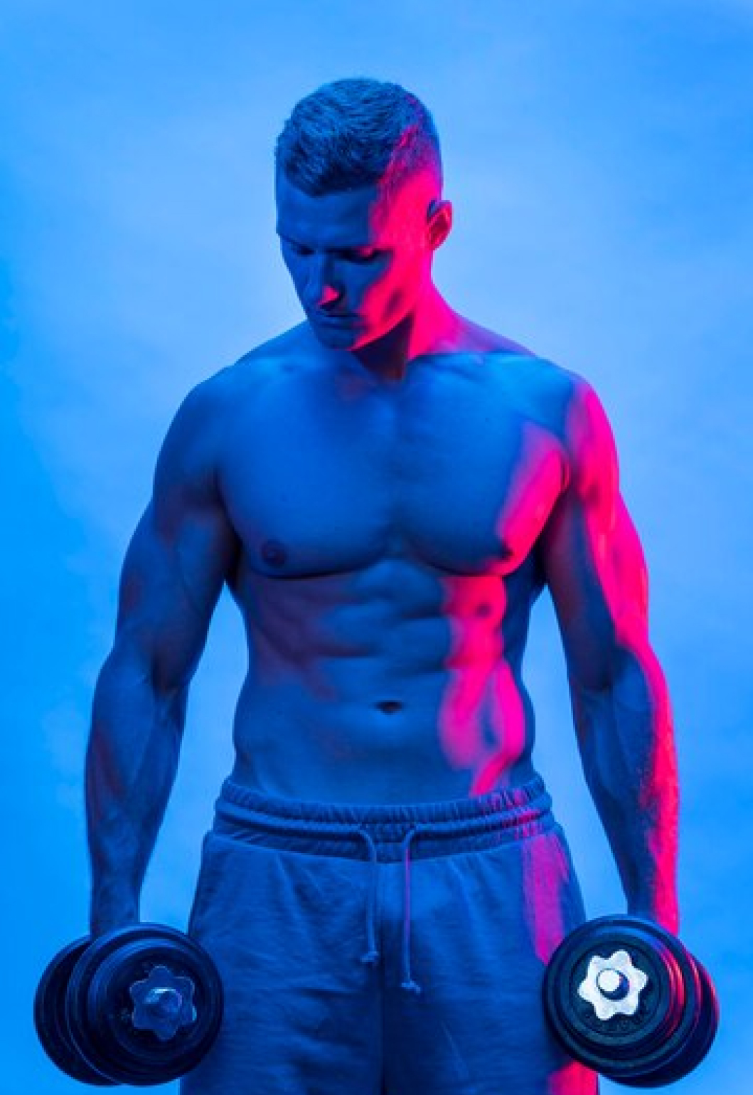 Спортивный мужчина держит в руках гантель